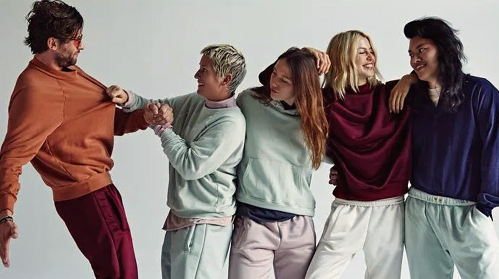 Models wearing various colors sweats from Les Tien stand and laugh.