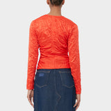 A model wear's GANNI's vibrant red crinkle satin blouse featuring a V neckline and front bodice tied with red satin bows - back view.