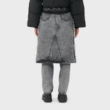 A model wears the acid washed black denim jeans with attached midi skirt with black boots - back view.