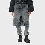 A model wears the acid washed black denim jeans with attached midi skirt with black boots.