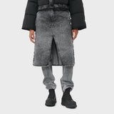 A model wears the acid washed black denim jeans with attached midi skirt with black boots.