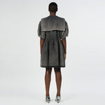 Back full body photo of model wearing a mini denim acid wash dress with a large collar and bow detail.