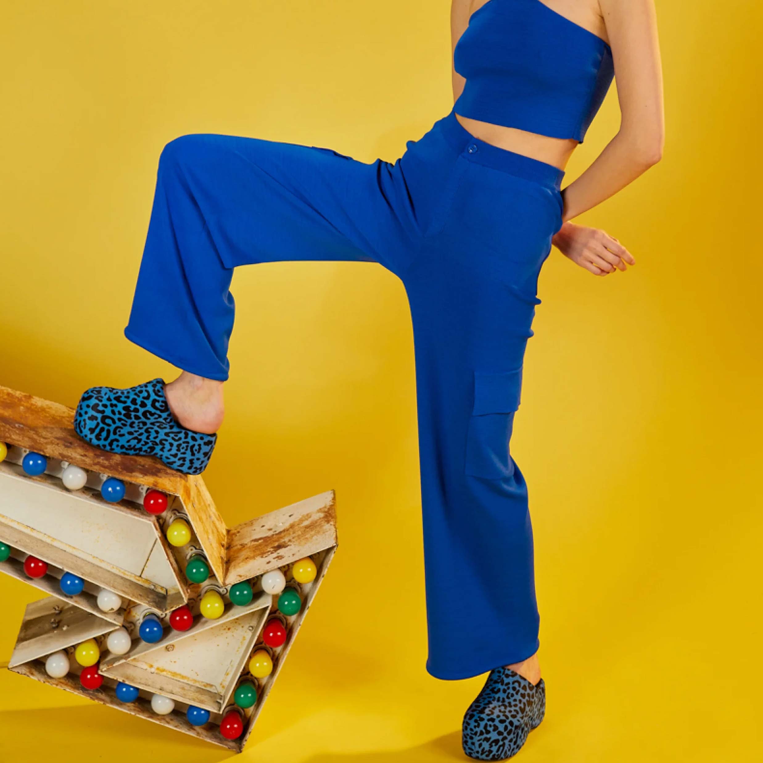 Close detail half body photo of the model wearing the Hesby Pant - a vibrant blue knit wide leg pant with side cargo-style pockets and a button & zip closure - from the SImon Miller lookbook.