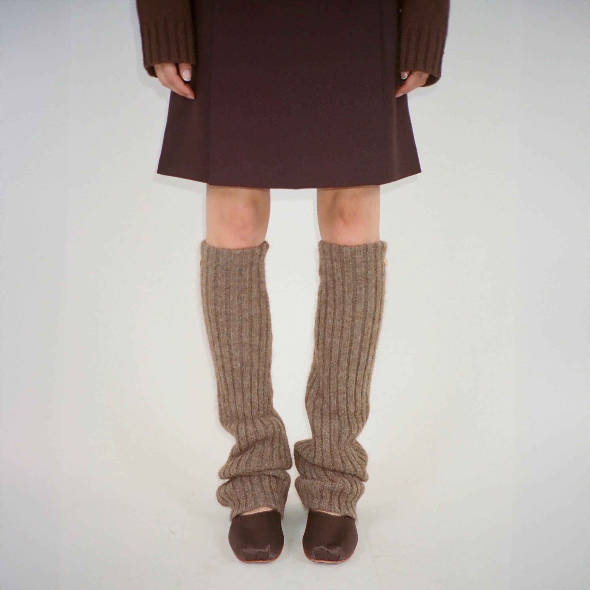 Front photo of model wearing the brown leg warmers paired with brown ballet flats and a brown skirt.