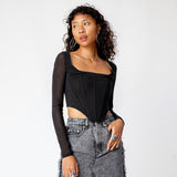 A model wears the long sleeved black mesh Maude Corset.