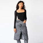 A model wears the long sleeved black mesh Maude Corset, paired with stone washed black jeans with overlaid skirt.