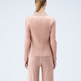 Back half body photo of model wearing the pleated polo top in the color beige.