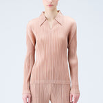 Close half body photo of model wearing a pleated polo top in the color beige.