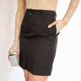 A model wears a dark grey fitted mini skirt designed with a pulled open front zipper - detail view.