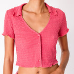 A model wears Misc Etc's pink ruched polo top in dark rose, paired with a matching pink mini skirt, close up view.