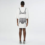 Back full body photo of model wearing the oversized white t shirt with a black graphic printed on the back.