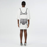 Back full body photo of model wearing the oversized white t shirt with a black graphic printed on the back.