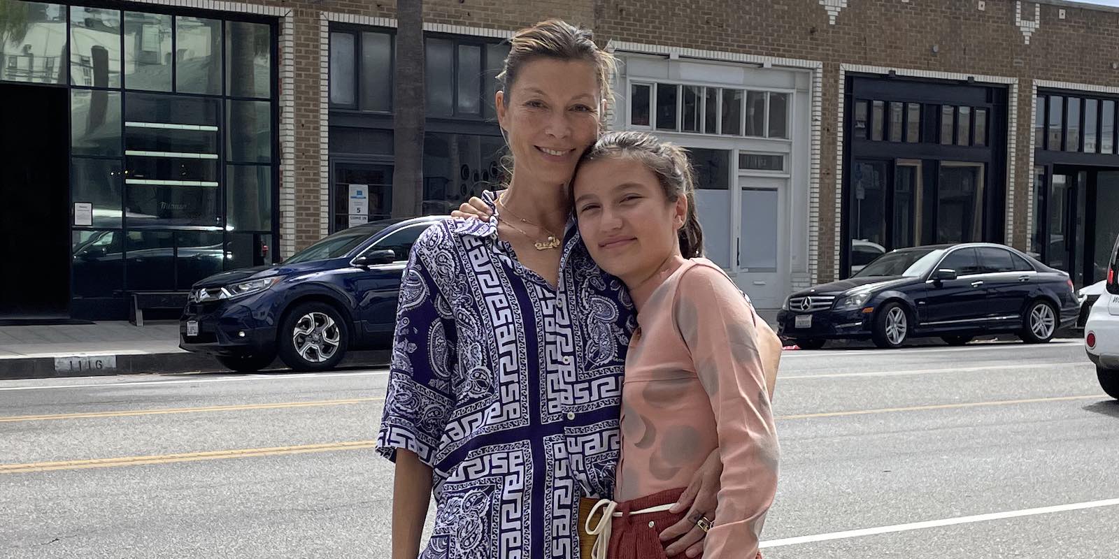 Mother and daughter stand roadside, wearing a navy blue and white printed button up shirt and pink and grey printed turtleneck top.