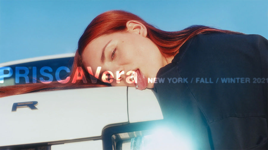 Campaign image from Priscavera of a model with red hair, laying atop a car, with the Priscavera logo on top.