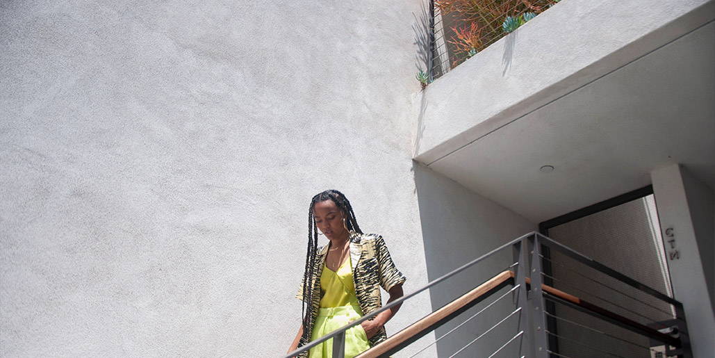 Photo of a model walking down stairs wearing GANNI printed short sleeve top.
