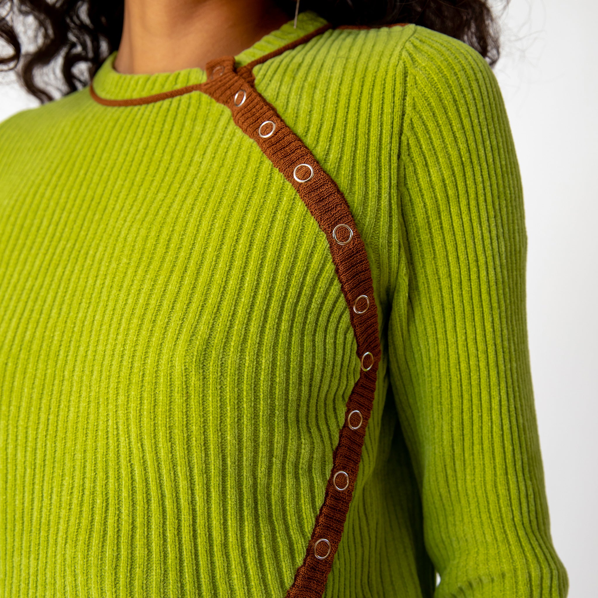 Close up detail of the ribbed lime green Angle Cardigan by Eckhaus Latta featuring buttons that flow in a curved line along the left side of the chest.
