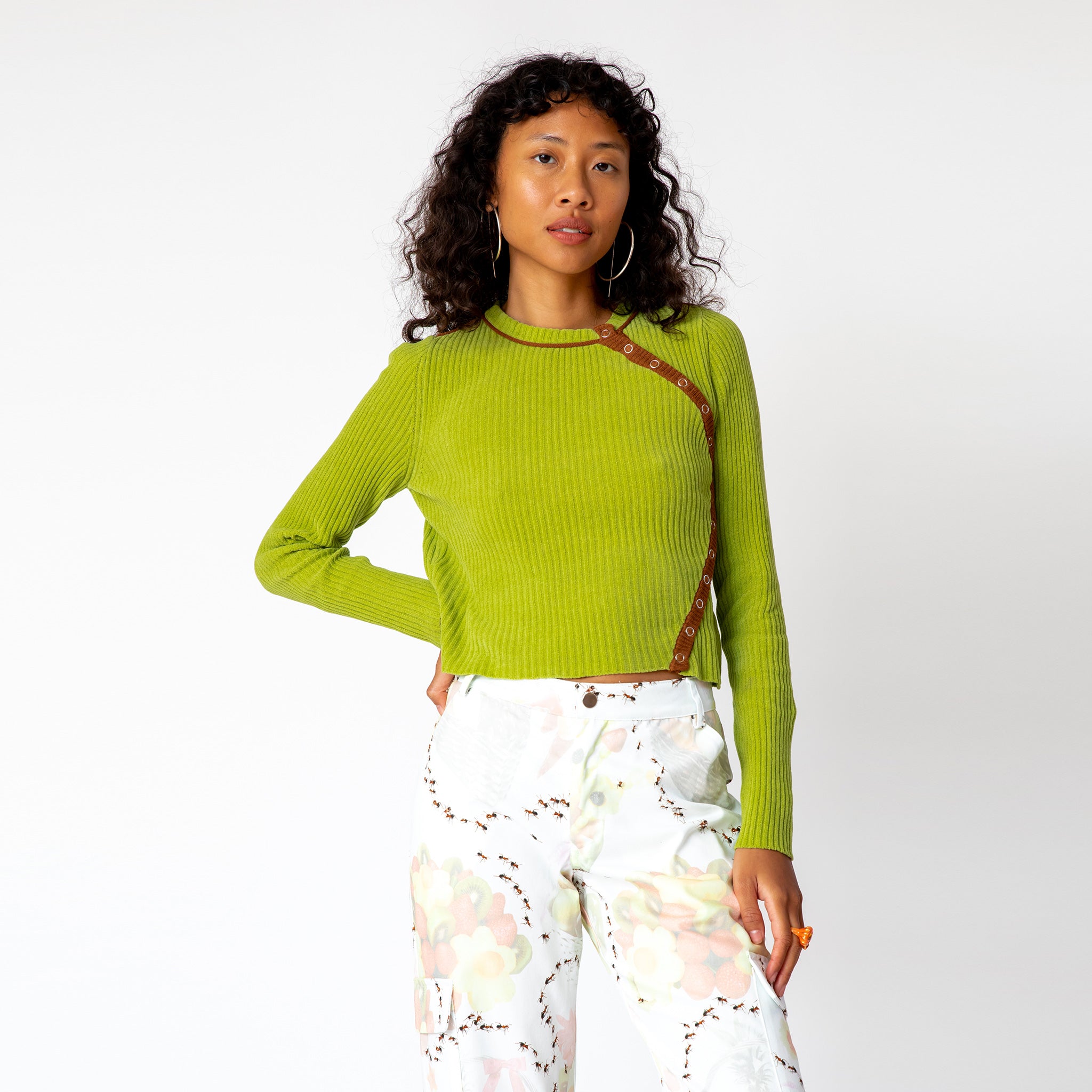 A model wears the ribbed lime green Angle Cardigan by Eckhaus Latta featuring buttons that flow in a curved line along the left side of the chest.