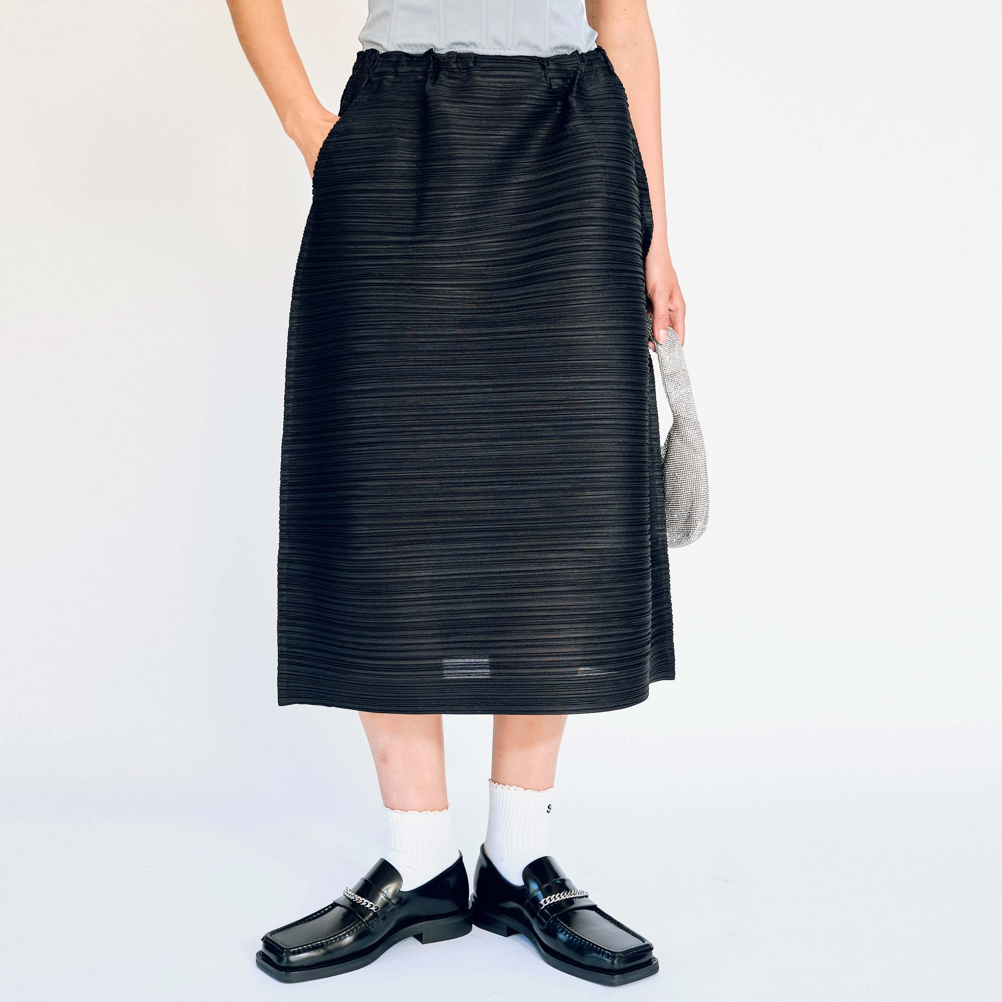 Horizontally pleated bouncy fabric black skirt by Pleats Please, front detail view on model.