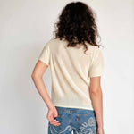 Classic Pleats Please Mist Top with slight mock neck and short sleeves in a light lemony cream color way - back view on model.