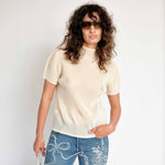 Classic Pleats Please Mist Top with slight mock neck and short sleeves in a light lemony cream color way - front view on model.