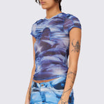 A model wears the blue and white graphic printed mesh Arc top, with ruching details along the chest and shoulders.