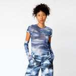 A model wears the blue and white printed mesh Arc Top by Collina Strada with matching cargo pants and gloves.