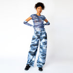 A model wears the blue and white printed mesh Arc Top by Collina Strada with matching cargo pants and gloves - full outfit view.