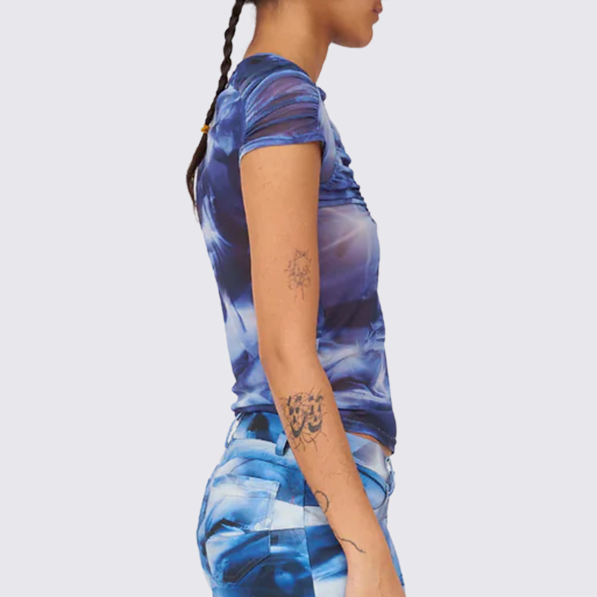 A model wears the blue and white graphic printed mesh Arc top, with ruching details along the chest and shoulders, side view.