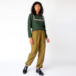 Full body photo of model wearing the green cable knit sweater with a pink lace collar and green cargo pants paired with black loafers.