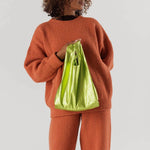 Close half body photo of model holding the Baby Baggu - UFO Metallic.