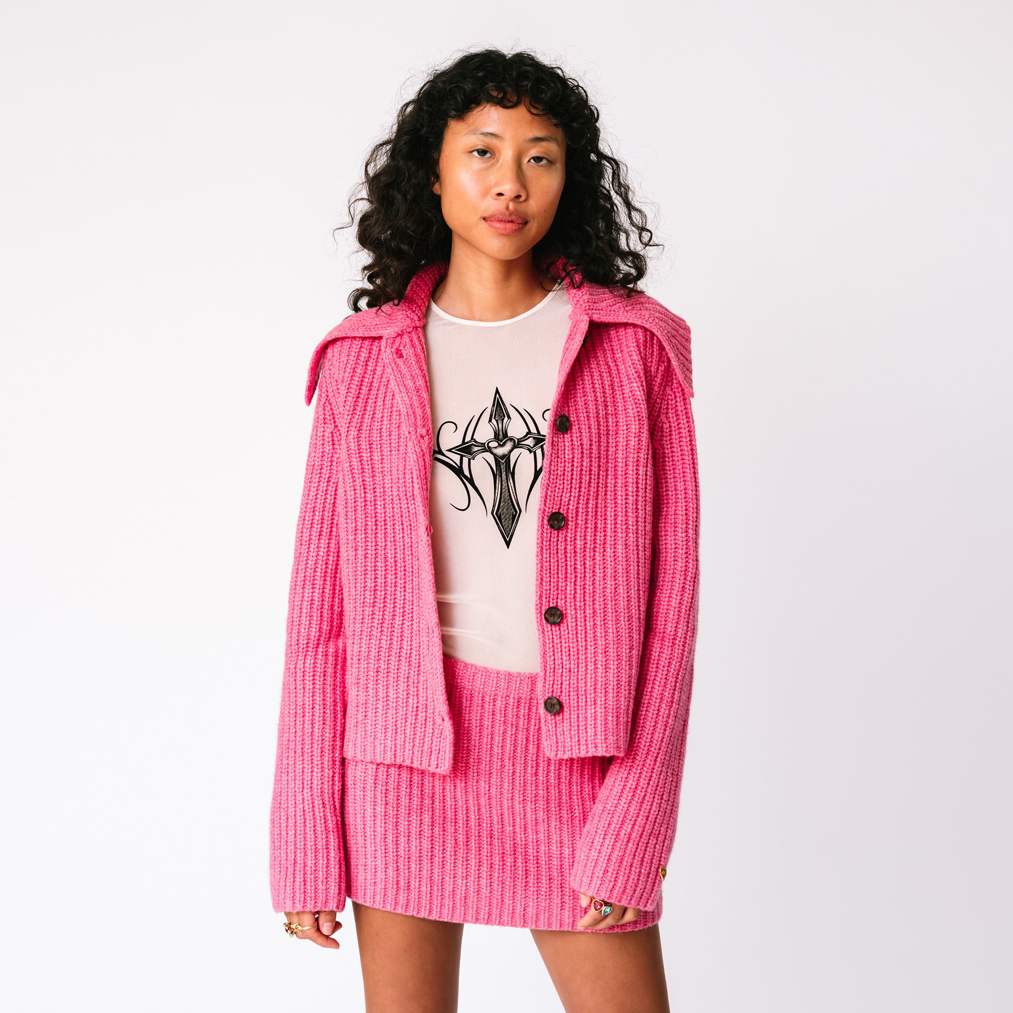 A model wears the Barb chunky ribbed pink skirt with the matching chunky ribbed pink Paw Cardigan, full outfit view.