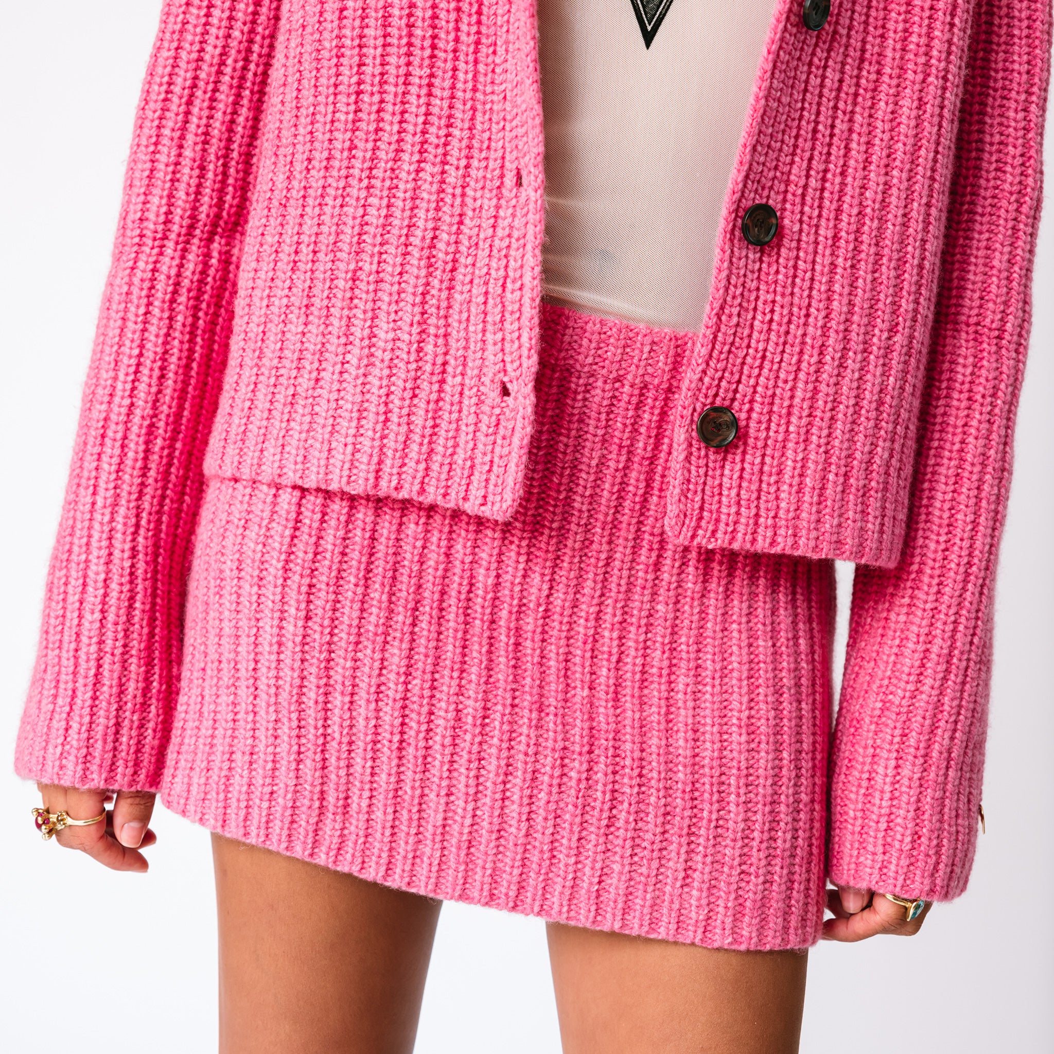 A model wears the Barb chunky ribbed pink skirt with the matching chunky ribbed pink Paw Cardigan, front view.