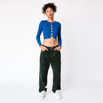A model wears the Big Ol' Jeans in washed black canvas in a baggy fit, paired with a cropped blue sweater and white sneakers.