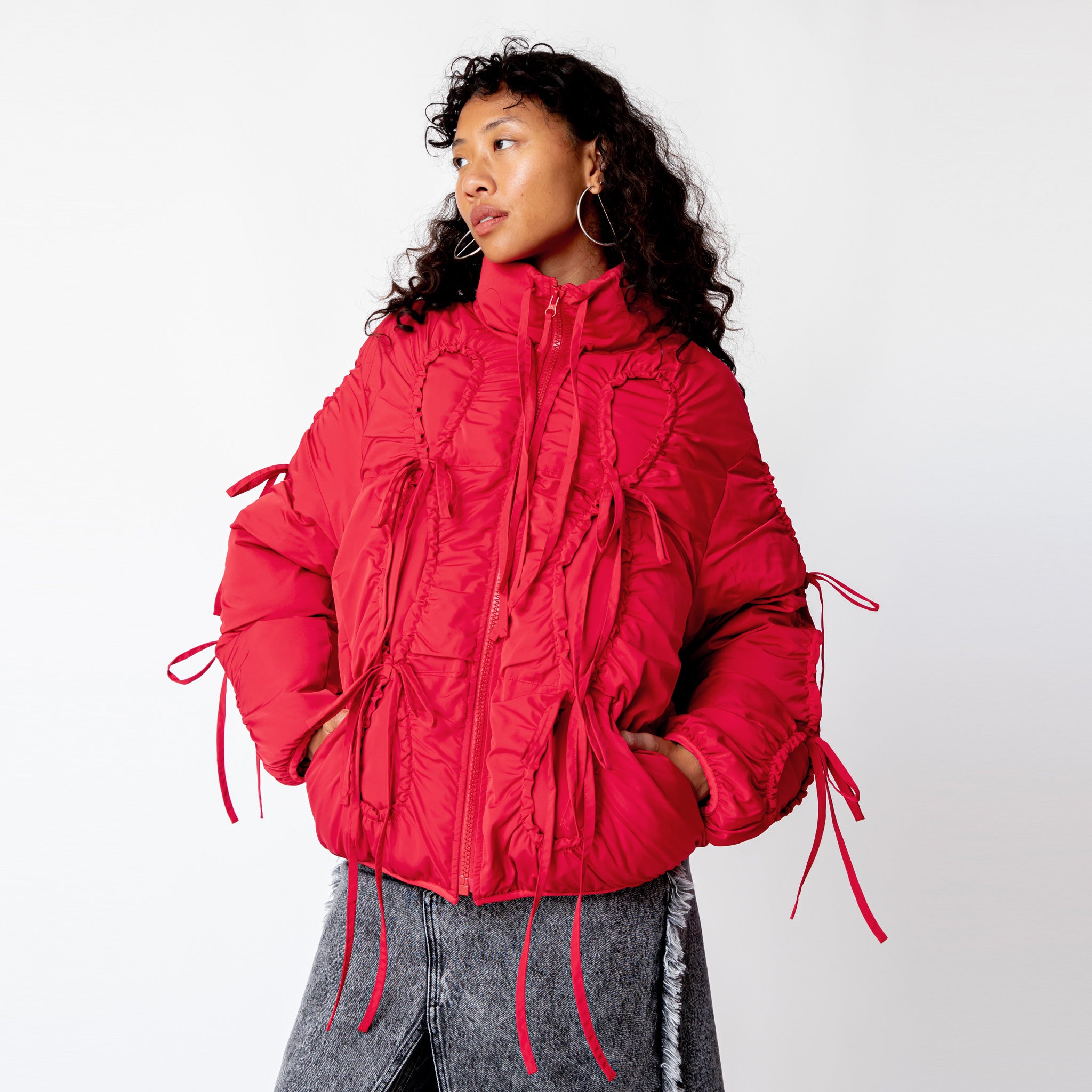 Half body photo of model wearing the Bommy Jacket - Red. The jacket features red bows all over the jacket.