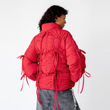 Back half body photo of model wearing the red bommy jacket with red bow details.