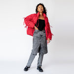 Full body photo of model wearing the bommy jakcet in the color red. This is styled with balck ganni acid wash pants with a skirt overlay. 