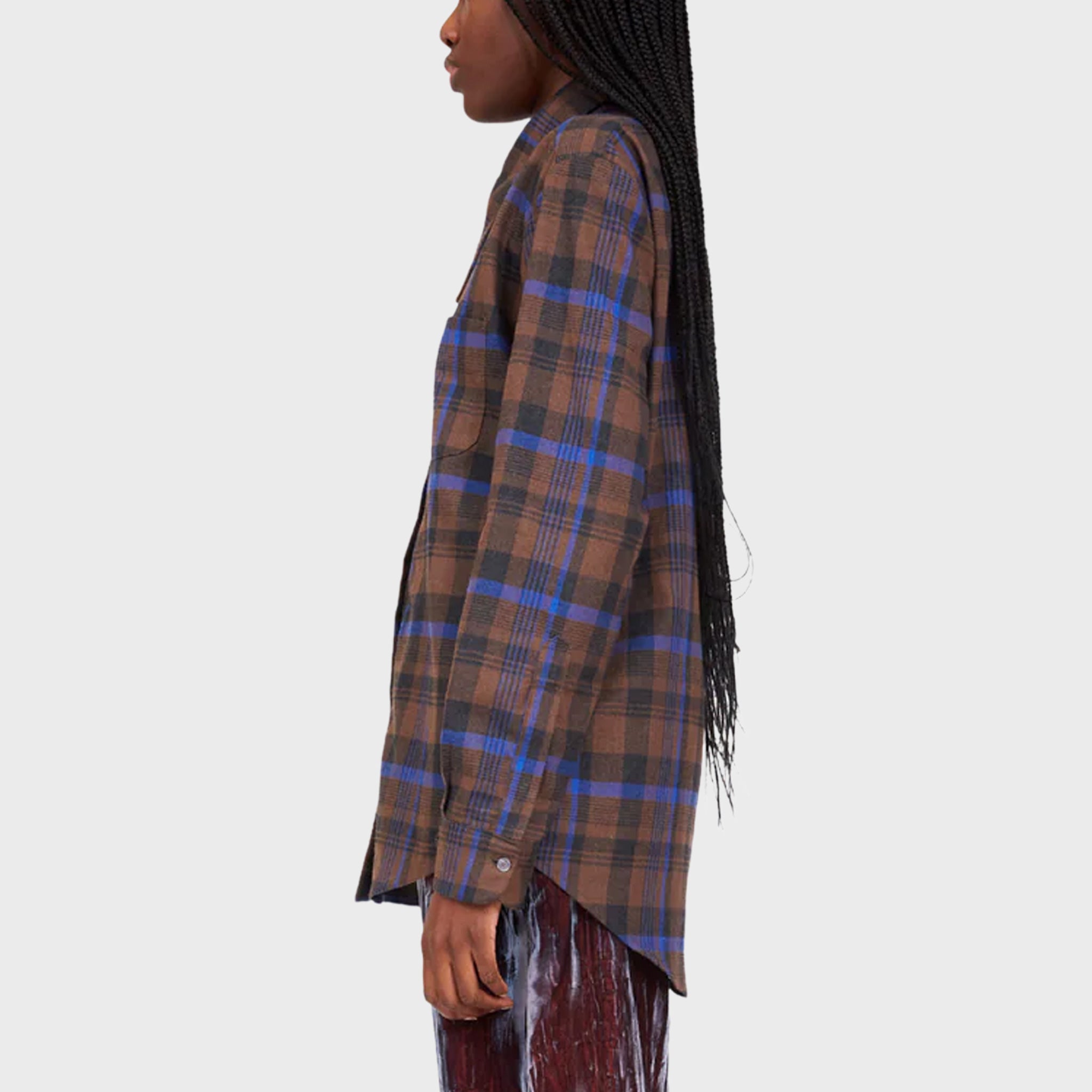 A model wears a brown and blue plaid flannel cotton shirt with an elongated collar that drops down like soft bunny ears - side view.