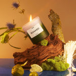 Photo of the Candle - Soaked sitting on a wood piece with various florals coming out of it. 