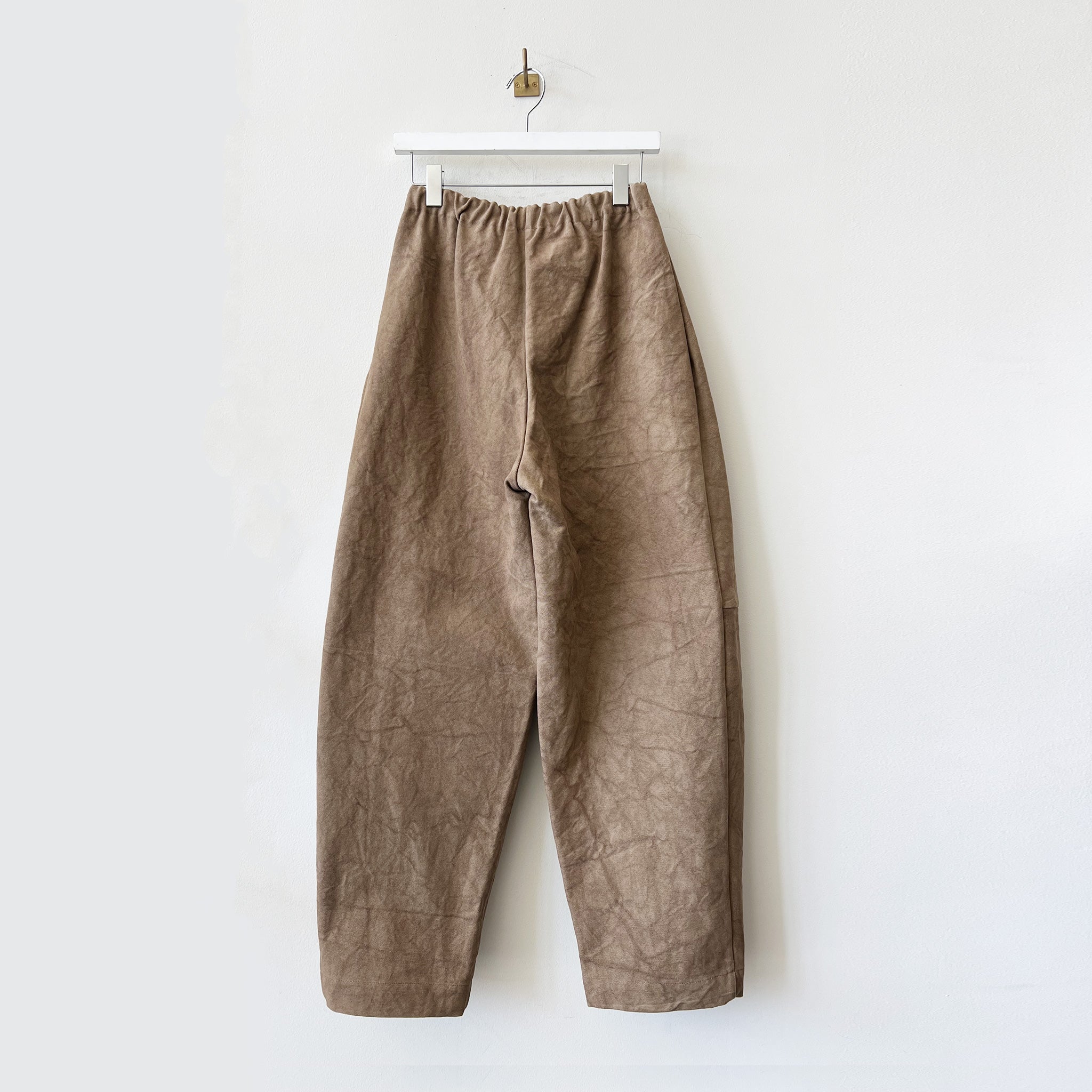 Brown crinkled cotton canvas pants with stitching across the knee and an exaggerated balloon-like shape - back view.