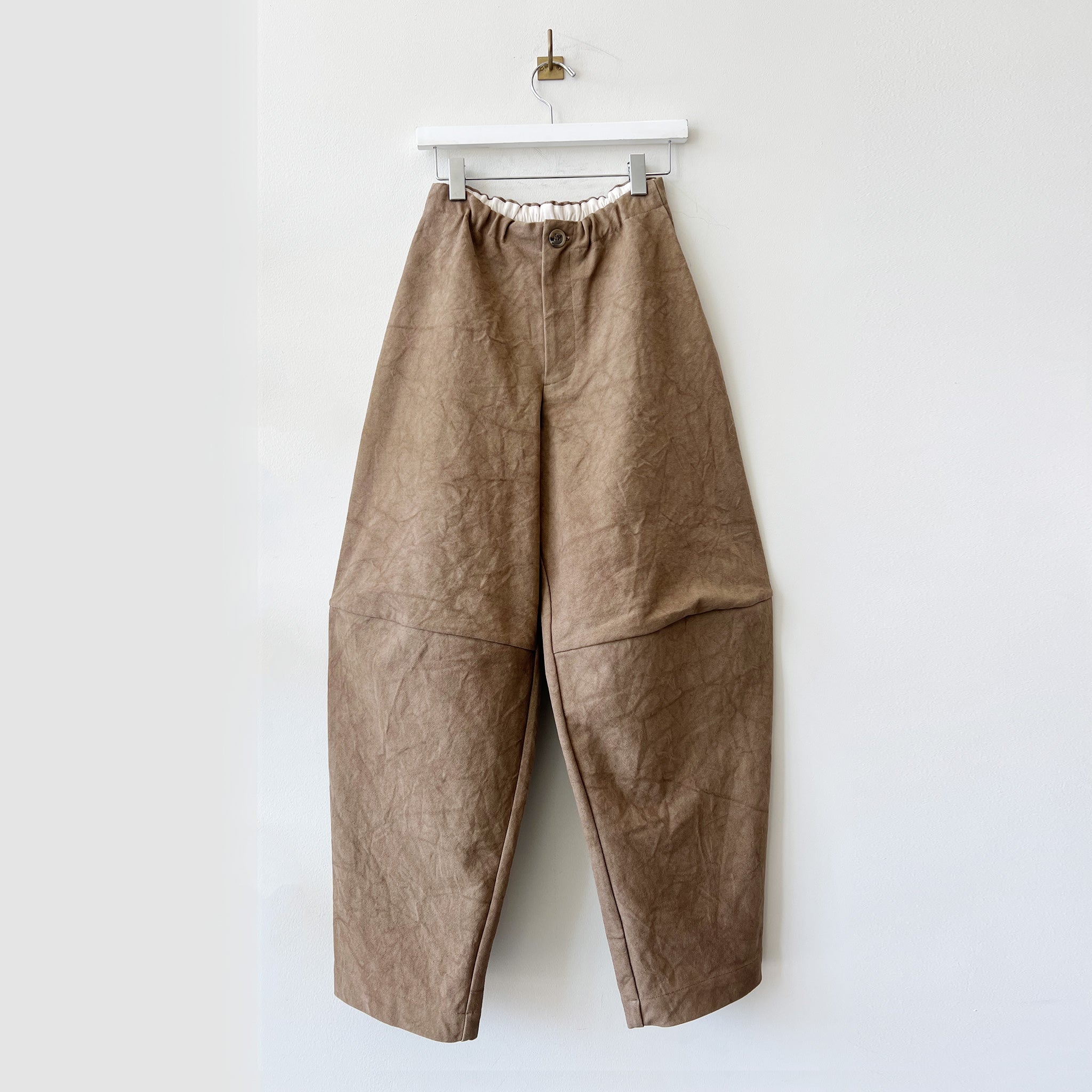 Brown crinkled cotton canvas pants with stitching across the knee and an exaggerated balloon-like shape.