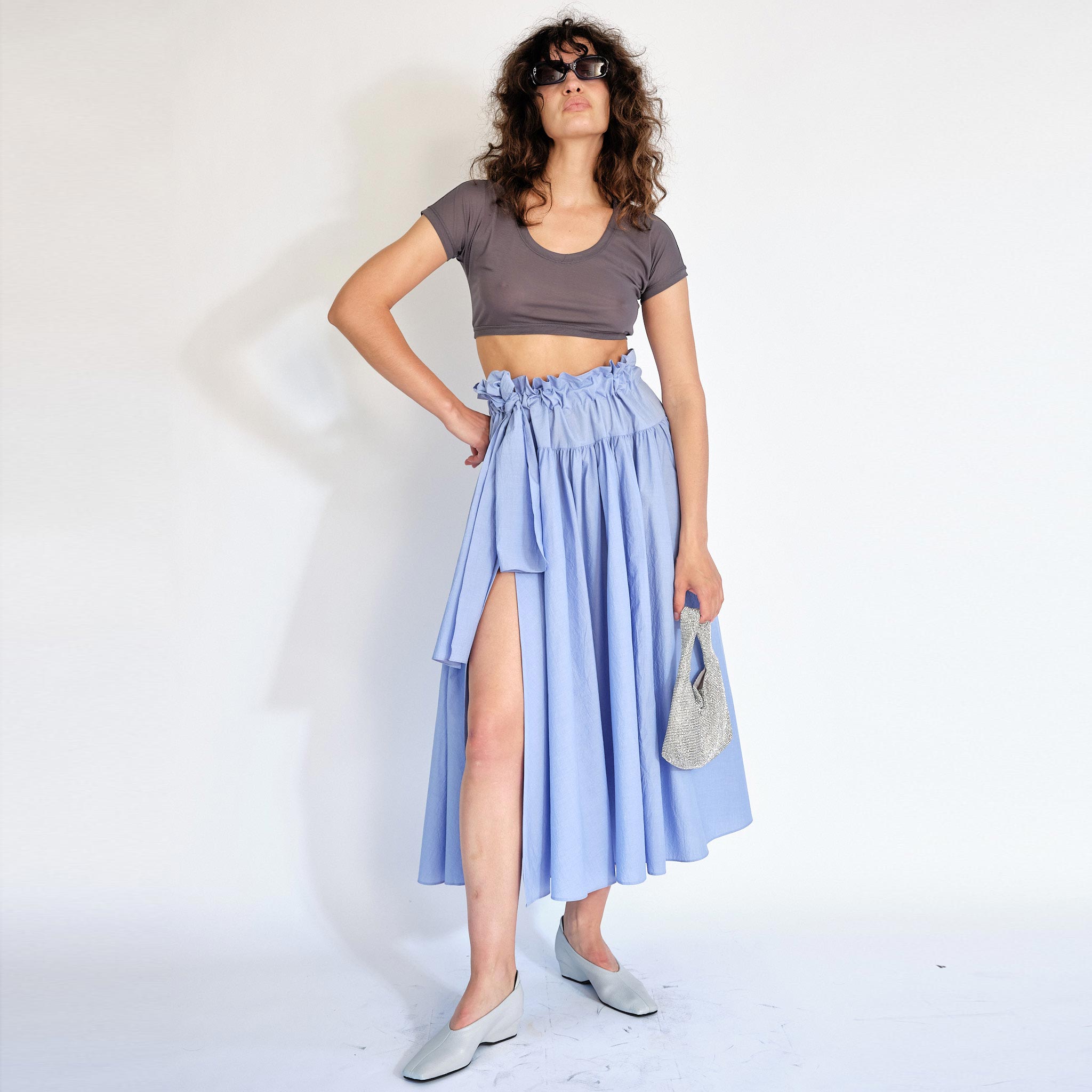 A model wears the Carlita Skirt, with a ruched, paperbag style waist and built in tie, with a side slit opening - full outfit view.