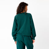 A model wears the classic raglan sweatshirt by Les Tien in an emerald green color - back view.