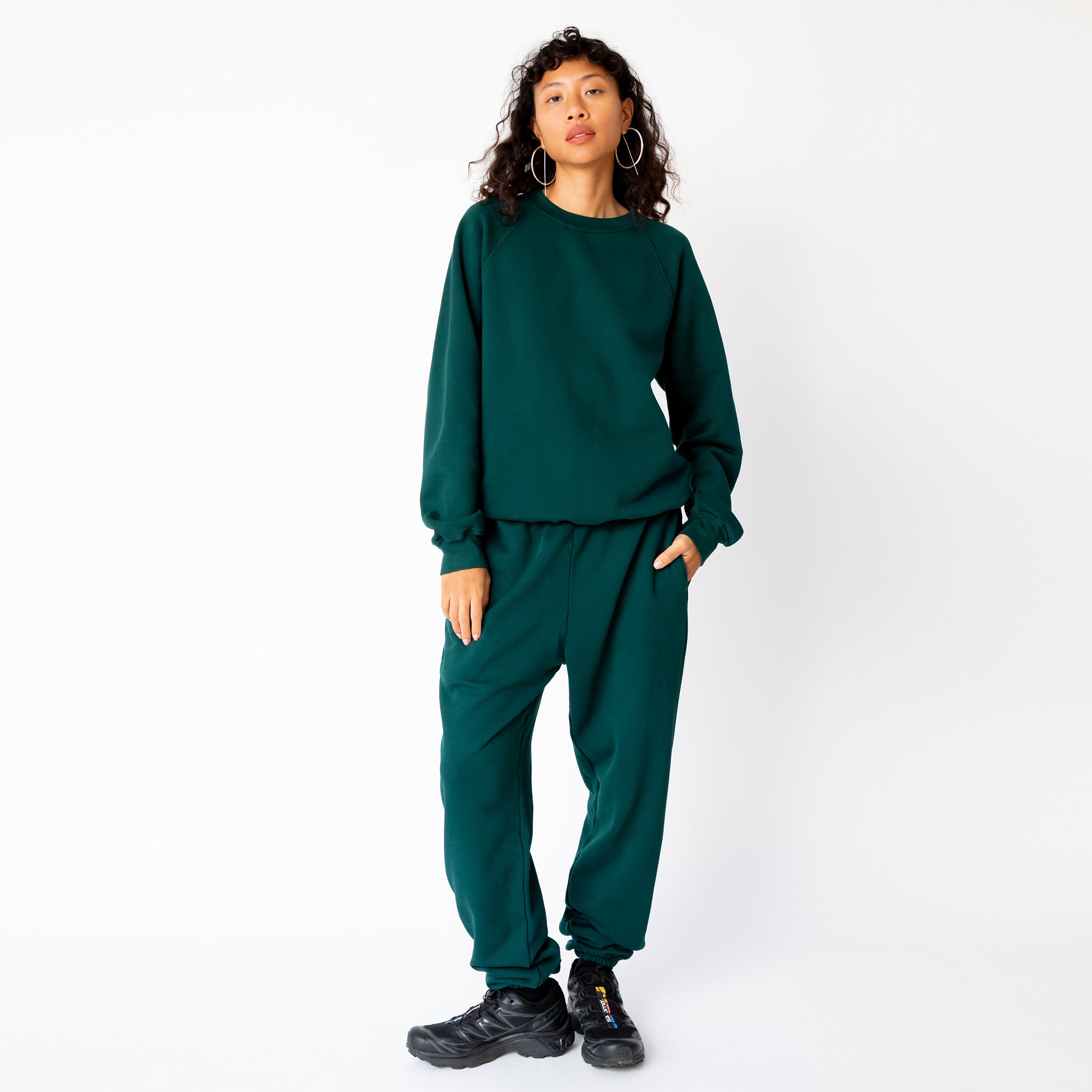 A model wears the classic raglan sweatshirt by Les Tien in an emerald green color - full outfit view, paired with matching sweatpants.