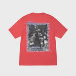 Flat photo of a red stussy t shirt with a graphic on the back featuring a black and white photo of kids in a class room. 