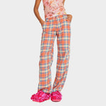 A model wears the peach and blue plaid printed Clover Pant, paired with the feathered Dachi printed top.