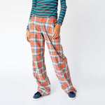 A model wears the coral plaid wide leg Clover Pant by Collina Strada, paired with a blue striped long sleeve - front detail view.
