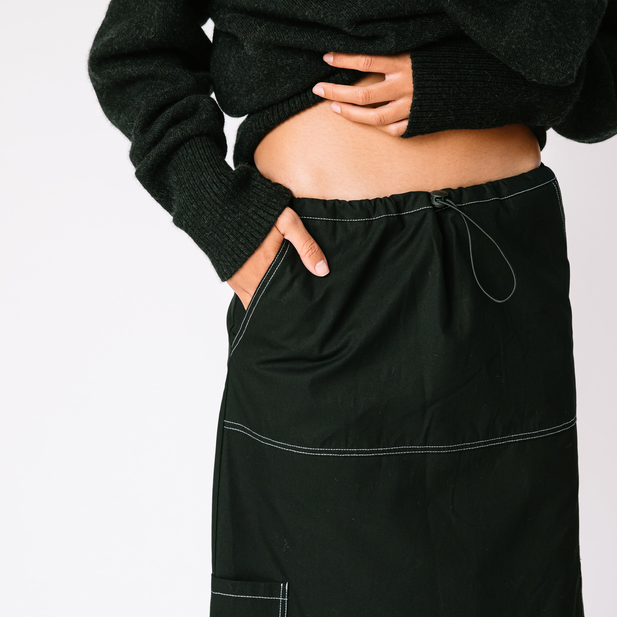A model with her hand in the pocket of the Misc Etc long Contrast Stitch Cargo Skirt in black.