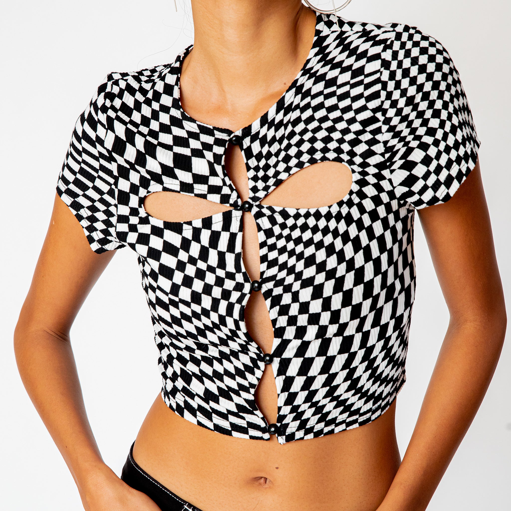 A model wears the black and white checkered cut out tee by Misc Etc, close up of cut outs.