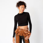Full outfit view of a model wearing the longsleeved black crop Mockneck top paired with brown and black gradient jeans and a velvet pleated belt.