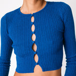 A model wears the electric blue cropped cardigan with multiple cutouts in a vertical line along the chest, detailed close up.